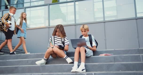 캠퍼스 공원을 산책하면서 즐거운 고등학생 집에가는 코카서스 소년과 십대의 귀여운 — 비디오