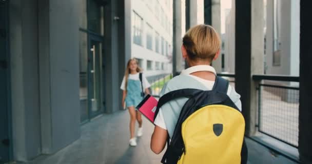 一个带着背包跑去现代学校大楼的男同学和一个要去见女孩的同学打招呼 并给了她一个高分 慢动作 — 图库视频影像