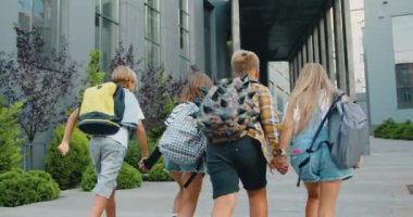 Neşeli ve enerjik bir grup öğrenci kız çocuk okul çantalarıyla modern kampüs okuluna gidiyor. Çocuklar birbirleri ile okulun önünde tanışırlar. Okul eğitimi çocuk konseptine geri dönelim. Yavaş çekim.