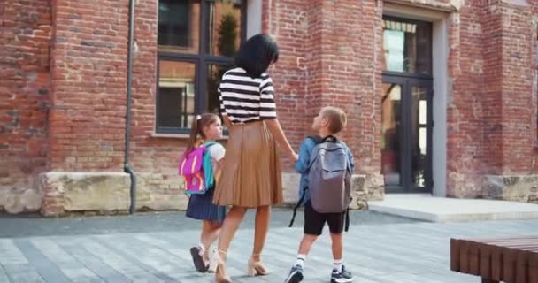 Dzieci Plecakami Trzymają Matkę Rękę Szczęśliwa Rodzina Mama Dzieci Chodzą — Wideo stockowe