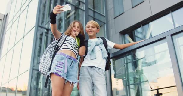 귀여운 재미있는 청소년 소년과 소녀는 사진을 스마트 카메라에 얼굴을하는 배낭과 — 비디오