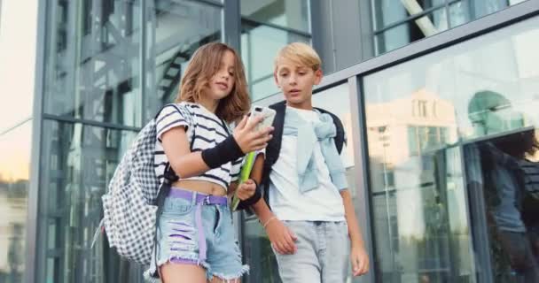 Söta Smarta Barn Pojke Och Flicka Med Skolväskor Och Smartphone — Stockvideo