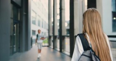 Genç öğrenciler okul yakınlarında buluşup selamlaşıyorlar, konuşuyorlar ve dışarıda beşlik çakıyorlar. Sırt çantaları ve laptoplarıyla okula giderken gülümseyen ve birbirini selamlayan pozitif okul çocukları.