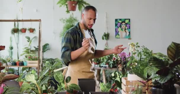 有魅力的非洲裔美国人在花店当花匠 为种植围裙的植物添加肥料 在围裙舞蹈和花卉市场工作的男花匠 慢动作 — 图库视频影像