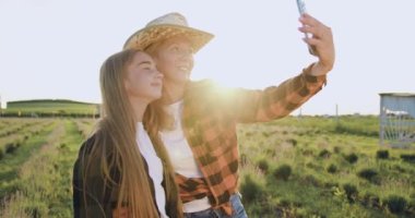 Yakın plan gülümseyen kız ve anne akıllı telefondan selfie çekiyorlar. Gün batımında yeşil alanda telefon kamerasına poz veren komik kız ve kadın. Pozitif aile bir alanda görüntülü konuşma yapıyor