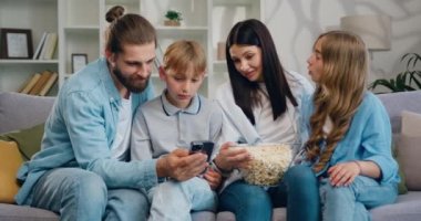 Çocukları cep telefonu kullanan ve birlikte yaşayan beyaz bir çift. Neşeli anne, baba, oğul ve kız kanepede otururken patlamış mısır yiyorlar. Yavaş