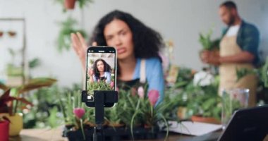 Gülümseyen kadın sosyal medya blog tasarımcısı çiçekçi akıllı telefondan yeni video çekiyor, bahçıvanlık ve ekimden bahsediyor. Kadın bahçıvan canlı yayında video, konferans çağrısı ya da yaratıcı