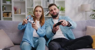 Mutlu bir aile kanepede oturup video oyunu oynuyor. Yetişkin erkek ve kadın PlayStation tutucu konsolu kullanıyor. Evde birlikte oyunlar, kadın ve erkek, mutlu aile. Yavaş çekim