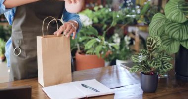 Kapatın. Afro-Amerikalı kadın çiçekçi, kese kağıdına sarılıp erkek alıcıya hediye olarak çiçek almayı öneriyor. Çiçekçi kadın, ev bitkisi satıyor. Küçük işletme, ev dekorasyonu