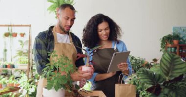 Çiçekçilerde dijital tablet bilgisayar kullanarak fabrikalarda çalışan iki profesyonel çiçekçi ve kadın. Seradaki mutlu iş arkadaşlarıyla takım çalışması ve işbirliği. İki başarılı meslektaşım