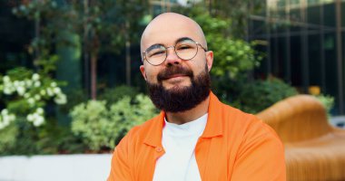 Caddede durup kameraya bakan gözlüklü yakışıklı bir adamın portresi. Hippi yüzünü kapat düşünceli, güler yüzlü, yakışıklı adam..