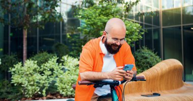 Bisiklet kiralama dijital telefon uygulaması kullanarak akıllı telefon tutan adam. Hipster Millennial 'daki genç adam akıllı telefona bakar. Kentsel yaşam tarzı kavramı.