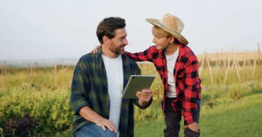 Çocuk babasına beşlik çakıyor. Oğul ve adam gün batımında sahada vakit geçiriyorlar. Siluet aile çiftçileri gün batımında bir buğday tarlasında bilgisayarla çalışıyorlar. Organik tarım ve aile kavramı