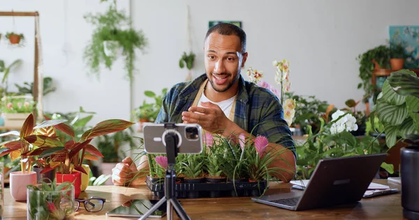 Small business entrepreneur owner man of plant shop streaming online shooting video for social networks using smartphone. Concept of floristry, retail small business and entrepreneurship.