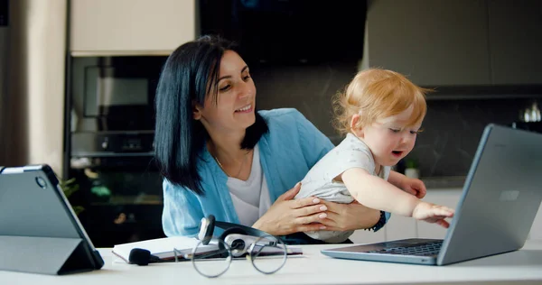 Work from home with family. Busy mother has difficulty working from home. Combining work responsibilities with raising child. Children help their freelance mother working.