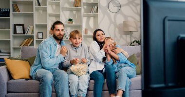 TV 'de korku filmi izleyip gözlerini kapatan dört kişilik çekici anne, baba, oğul ve kız çocuğu TV' de korkunç olaylar görmesinler diye..