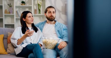 Mutlu çift, sarıl ve rahatla. Oturma odasındaki kanepede televizyon izle. Kadın ve erkek, kanepede rahat bir şekilde film, patlamış mısır ve uzaktan kumanda hakkında konuşur..