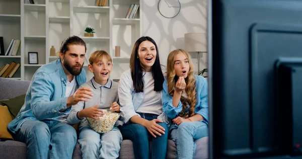 Fiatal Kaukázusi Szülők Gyerekeikkel Ülnek Kanapén Nappaliban Popcornt Esznek Tévéznek Stock Kép