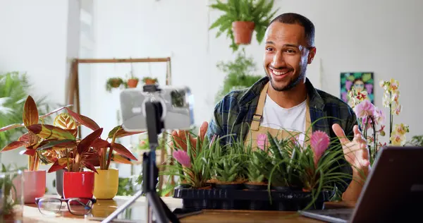 Small business entrepreneur owner of plant shop streaming online from workplace. Man entrepreneur florist broadcasting live on smartphone the presentation of potted plants for online shopping in