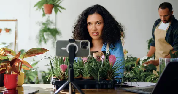 African American smiling woman florist blogger recording floristry video course, conference calling or streaming live creative web training lesson on smart phone. Owner woman using smartphone in