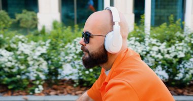 Gündelik giysiler içinde hippi bir adam ve sokakta bisiklet. Kulaklıklı genç adam şehir bölgesinde bisiklet sürüyor işe gidiyor..