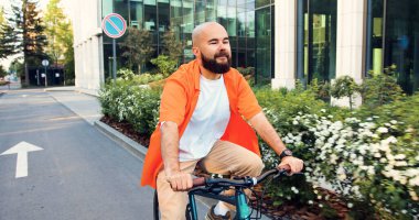 Gözlüklü genç sakallı hippi işe giderken bisiklet sürüyor. Şehir gezgini konsepti. Yakışıklı sakallı yönetici başarılı CEO işe bisikletle gidip geliyor..