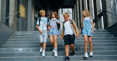 Portrait of smiling cheerful school children that hugging each other and smiling in camera, outdoors. Back to school concept clipart