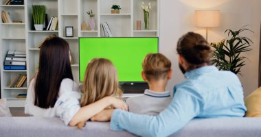 Çift evdeki kanepede birlikte oturuyor, kroma tuşlu yeşil ekranlı TV programları izliyorlar. Karı koca evde birlikte dinleniyor. Yeşil ekran. Kromakey. Ev sineması.