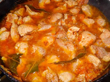 Kızartma tavasında baharatlı, soğanlı ve havuçlu domuz eti yakın planda pişirilir..