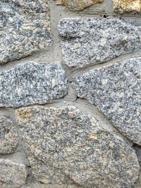Bu yapı, dayanıklı bir duvarda yerleştirilmiş yıpranmış granit taşları içeriyor, işçiliği vurguluyor..