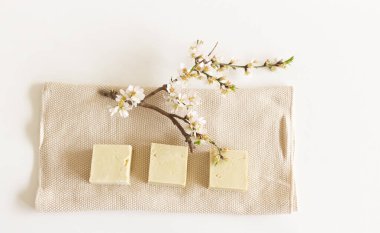 Closeup of hand made herbal soap. Almond twigs white table background. Spa concept. Skin product mockup scene cosmetic product.