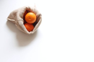 Mandarin, tangerine, clementine in a jute bag isolated on white background. Top view Natural food fruit for juices and jellies.