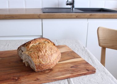 Ekmek yakın çekim. Mutfaktaki masada üzerinde altın bir kabuk olan taze pişmiş ekşi ekmek. Yiyecek konsepti.