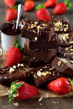 Chocolate brownie with strawberries on brown background