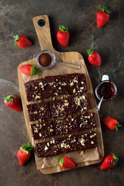 Chocolate brownie with strawberries on brown background