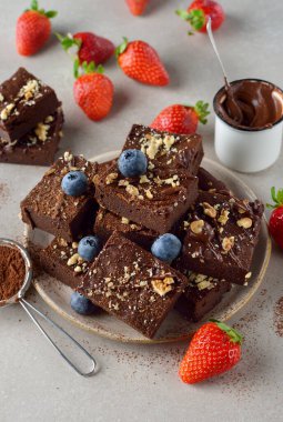 Chocolate brownie with strawberries on brown background