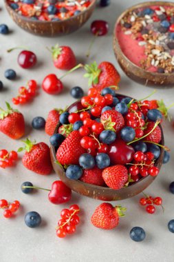 Gri arka planda bir kasede çeşitli bahçe meyvelerinin karışımı.