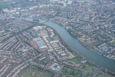 Londra 'nın kenar mahallelerinin havadan görünüşü sabahın erken saatlerinde bulutların arasından Thames nehrinin altın saatinde İngiltere' nin sanayi bölgesi yakınlarında yükselmesiyle