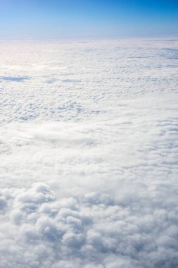 Uçak penceresinden bulutların görüntüsü, açık bir günde mavi gökyüzünde bulutlar.