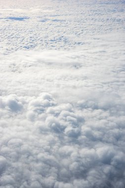 Uçak penceresinden bulutların görüntüsü, açık bir günde mavi gökyüzünde bulutlar.