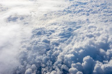 Uçak penceresinden bulutların görüntüsü, açık bir günde mavi gökyüzünde bulutlar.