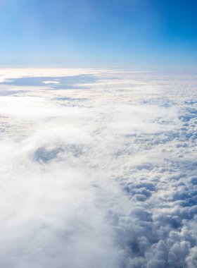 Uçak penceresinden bulutların görüntüsü, açık bir günde mavi gökyüzünde bulutlar.