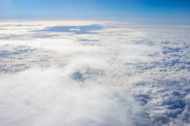 Uçak penceresinden bulutların görüntüsü, açık bir günde mavi gökyüzünde bulutlar.