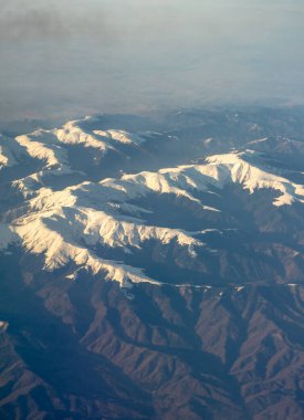 Avrupa 'da karla kaplı dağ zirvesi gökyüzünden izleniyor, bir dağ manzarası.