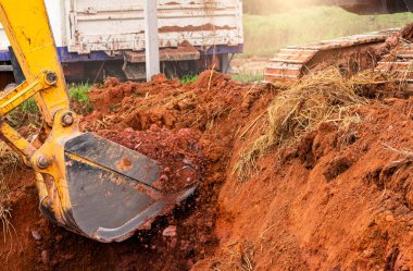 Excavator bucket digging soil for loading to truck. Earthwork. Dirt metal bucket of backhoe working at a construction site. Earthmoving machine. Earth excavation. Excavator digging on demolition site. clipart