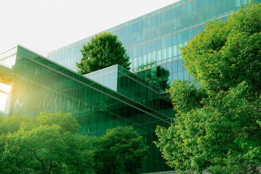 Sustainble green building. Eco-friendly building. Sustainable glass office building with tree for reducing carbon dioxide. Office with green environment. Corporate building reduce CO2. Safety glass. clipart