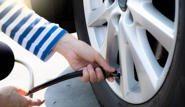 stock image Woman inflates the tire. Woman checking tire pressure and pumping air into the tire of car wheel. Car maintenance service for safety before travel. Tire inflating point. Filling air in the tyre of car