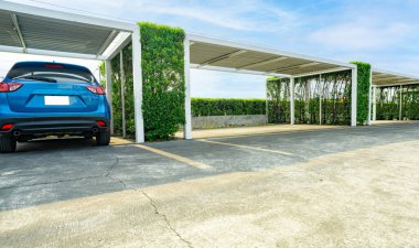 Boş yeri olan bir otopark. Güneşli yaz gününde park yeri ve boş alan. Yeşil çitli, açık hava otoparkında park edilmiş mavi SUV 'nin dikiz aynası. Çevre dostu açık otopark.