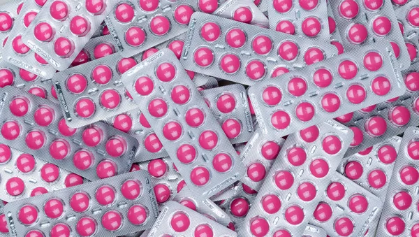 Full frame heap of round pink tablets pills in blister pack. Prescription drugs. Painkiller medicine. Pharmaceutical industry. Ibuprofen for pain treatment. Healthcare and medicine background.