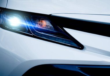 Lüks beyaz bir arabanın yakın farı. Otomotiv endüstrisi konsepti. Elektrikli araba ya da hibrit araç konsepti. Otomobil kiralama ve sigorta konsepti. Oto kiralama işi. Elektrikli araç.